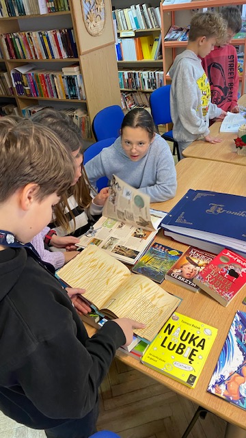 Dzieci siedzą przy stole w czasie lekcji bibliotecznej