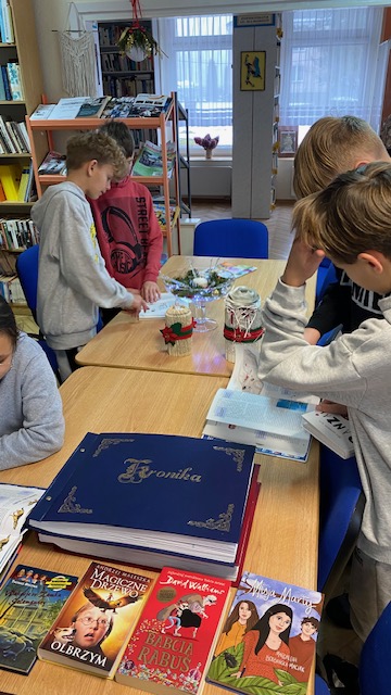 Dzieci siedzą przy stole w czasie lekcji bibliotecznej