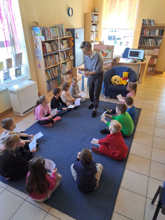 Bibliotekarz rozdaje dzieciom kolorowanki