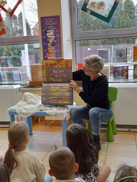 bibliotekarka pokazuje książkę z obrazkami podziemia