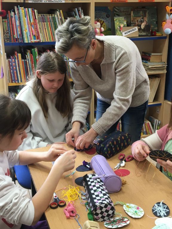 Dzieci wykonują pracę plastyczną z pomocą bibliotekarza