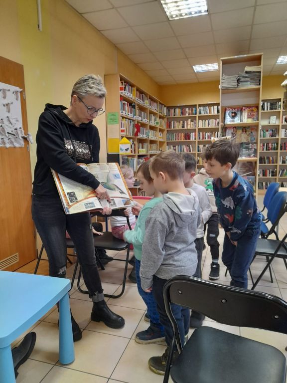 Bibliotekarz pokazuje dzieciom książkę z obrazami ptaków