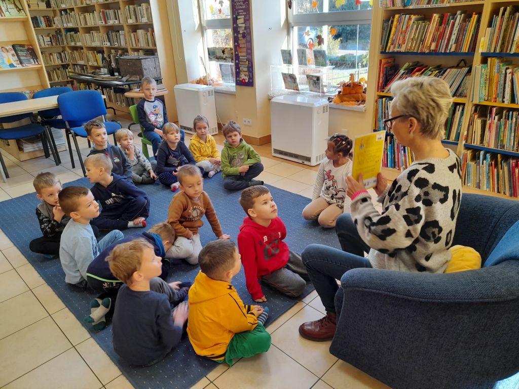 Bibliotekarz pokazuje dzieciom książki, na których oparte są zajęcia.