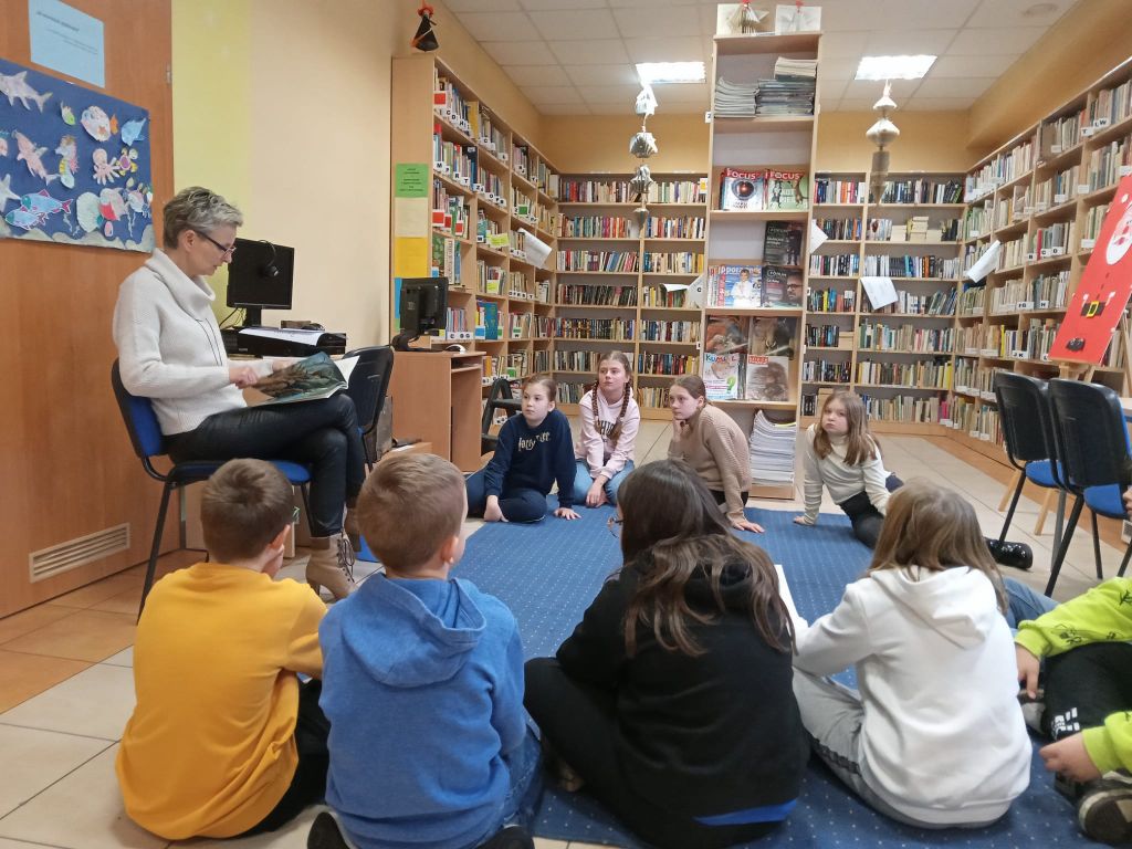 Bibliotekarz czyta dzieciom bajkę, o którą oparte są zajęcia.