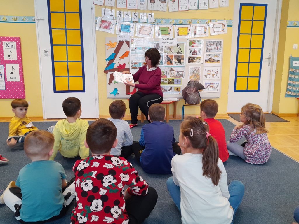 Bibliotekarz czyta dzieciom bajkę z książeczki