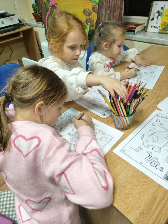 Grupa dziewczynek koloruje kolorowanki.