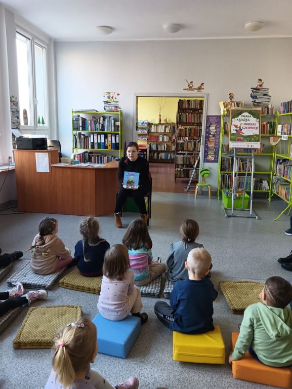 Bibliotekarka pokazuje dzieciom książkę z krasnalem