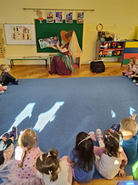 Bibliotekarka, przebrana za wróżkę, czyta książkę