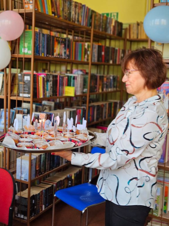 Bibliotekarz niesie babeczki z zapalonymi świeczkami 