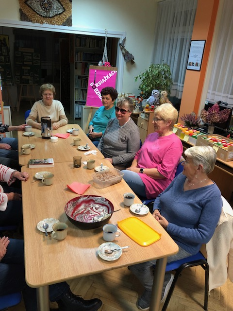 Uczestnicy spotkania siedza przy stole i rozmawiają o książce