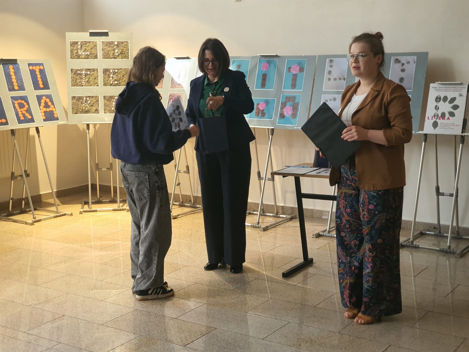 Bibliotekarka wręcza nagrodę uczestnikowi konkursu.