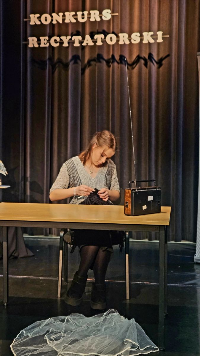 Dziewczyna w ramach wystąpienia pokazuje jak szydelkuje sweter