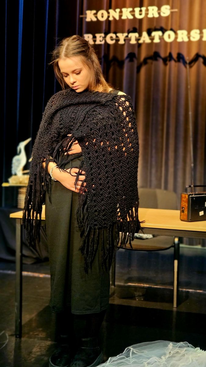 Dziewczyna ubrano na czarno trzyma się wymownie za brzuszek