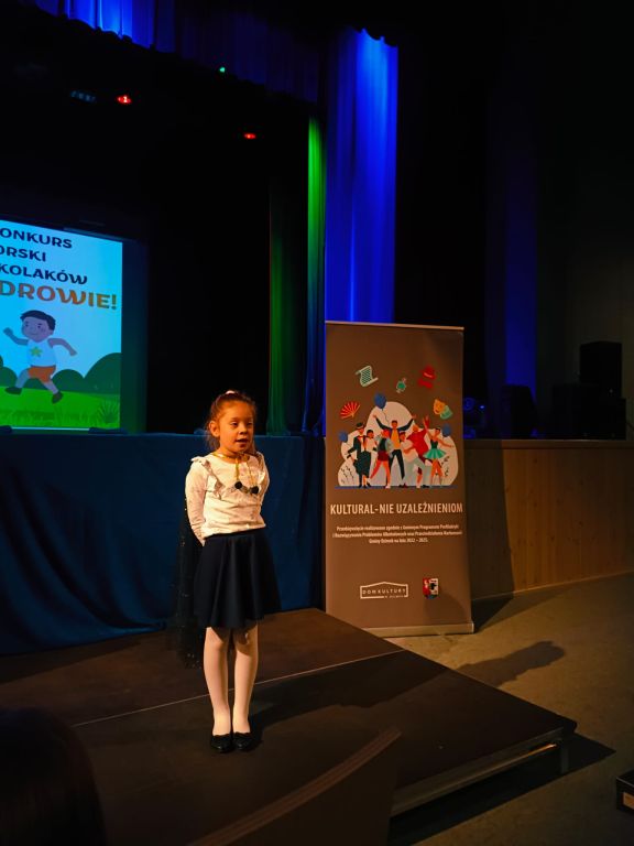 Dziewczynka stoi na podeście i recytuje wiersz