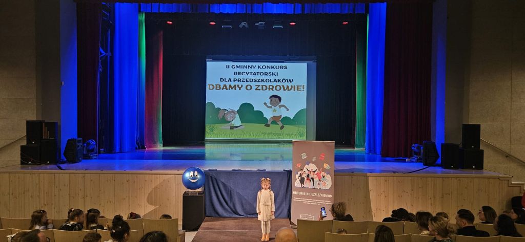 Dziewczynka stoi na podeście i recytuje wiersz