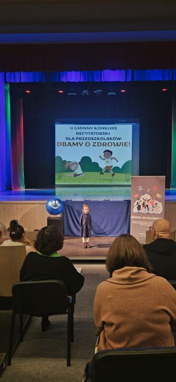 Dziewczynka stoi na podeście i recytuje wiersz