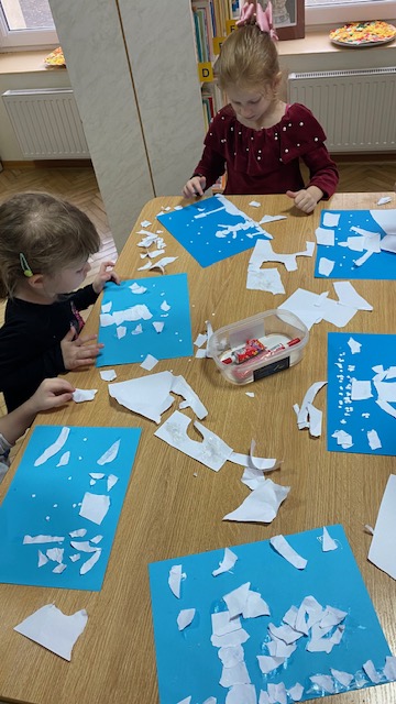 Na niebieskich kartkach robią zimowe widoki z białej wydzieranki