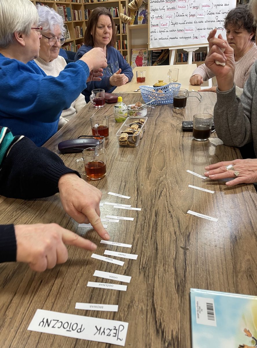  Grupa pań segreguje na blacie stołu słowa, przydzielając je do języka literackiego i potocznego.