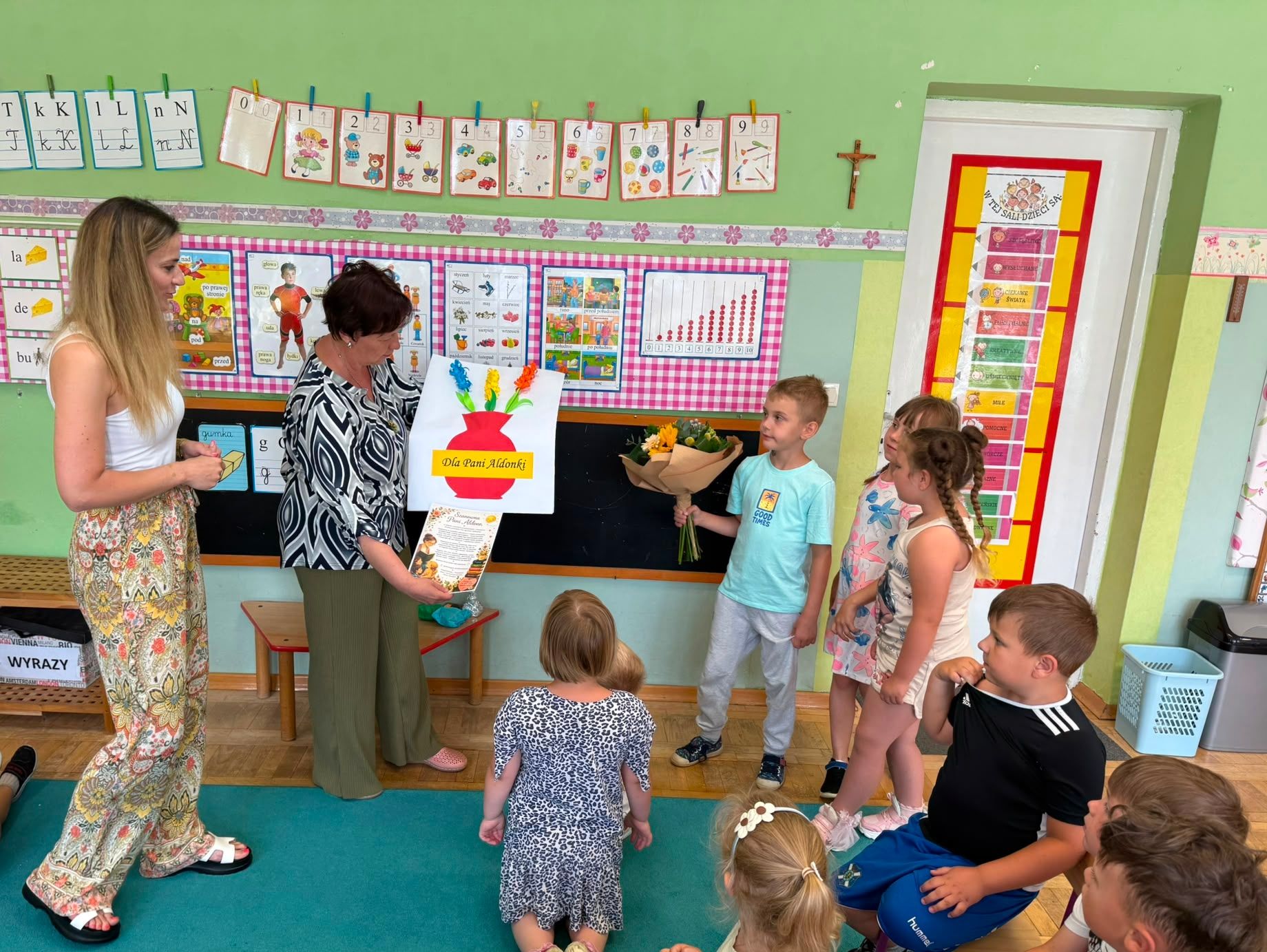 Pani bibliotekarka trzyma laurkę otrzymaną wcześniej od dzieci.