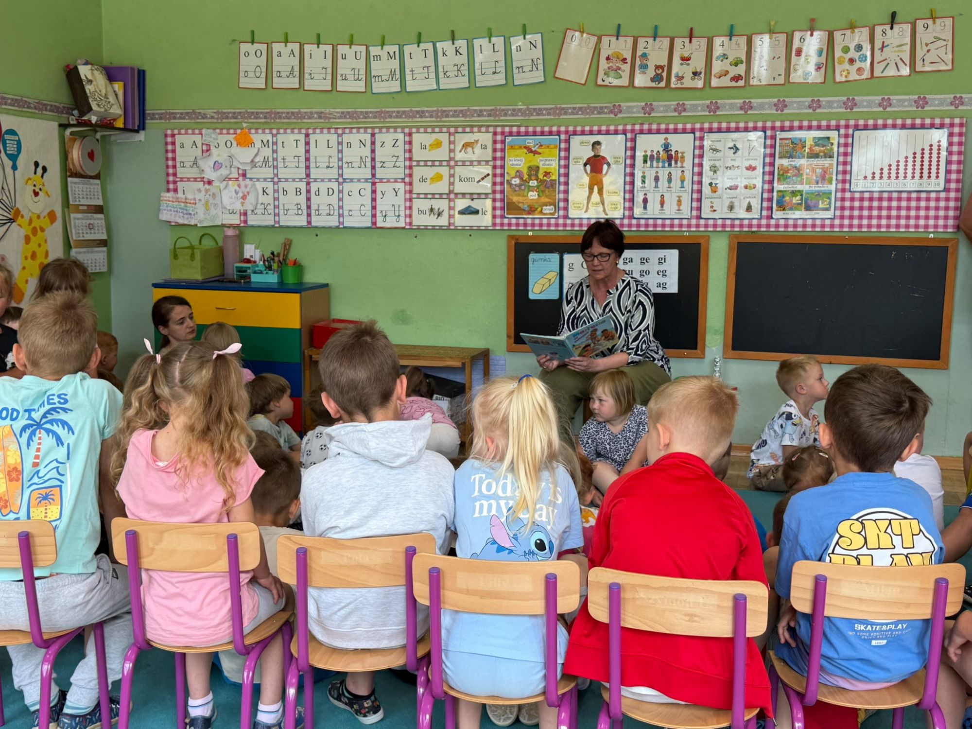 Pani bibliotekarka czyta książkę przedszkolakom o bezpiecznym wypoczynku nad morzem.