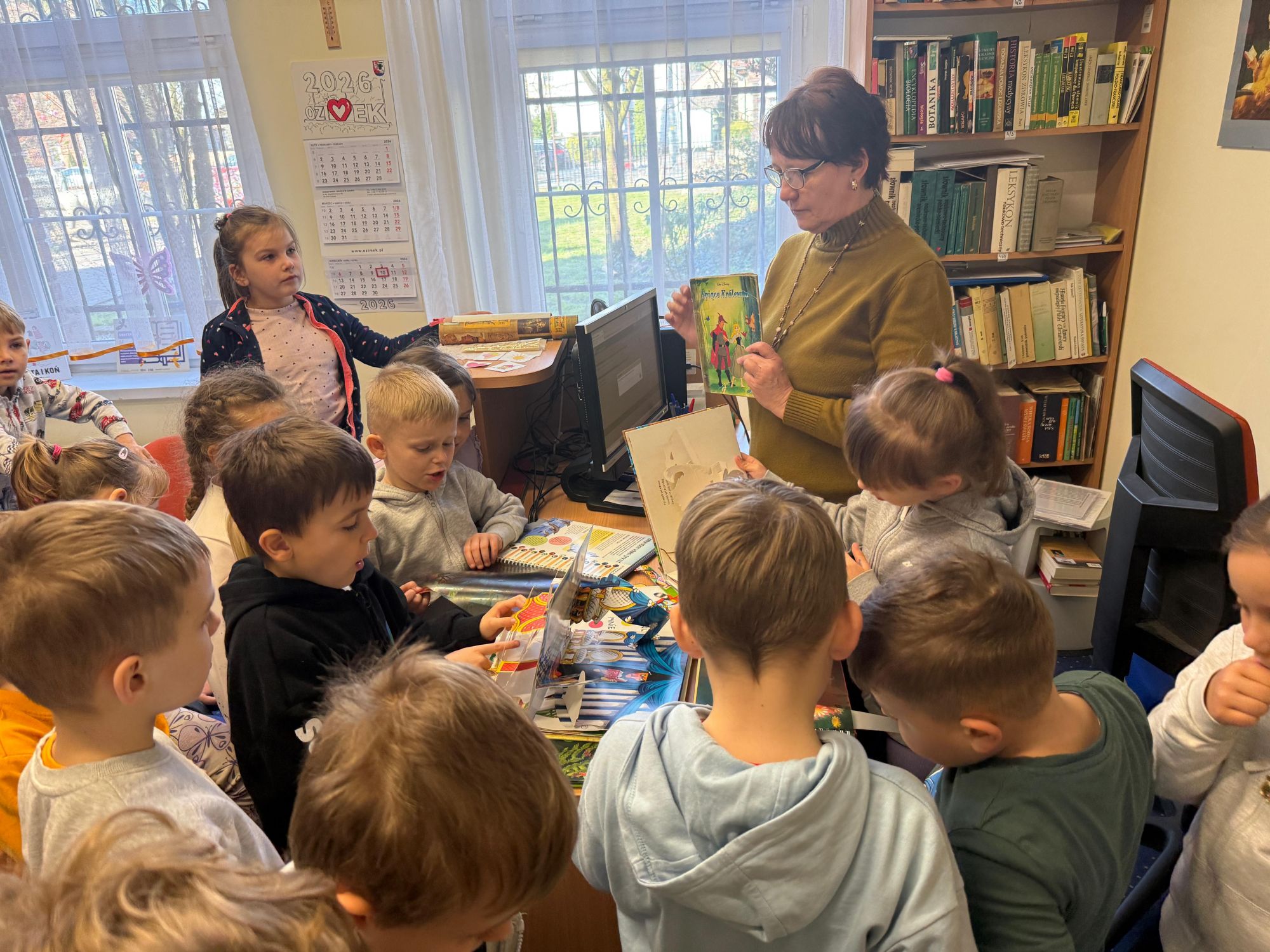 Bibliotekarka uczy dzieci jak naprawiać zniszczoną książkę.