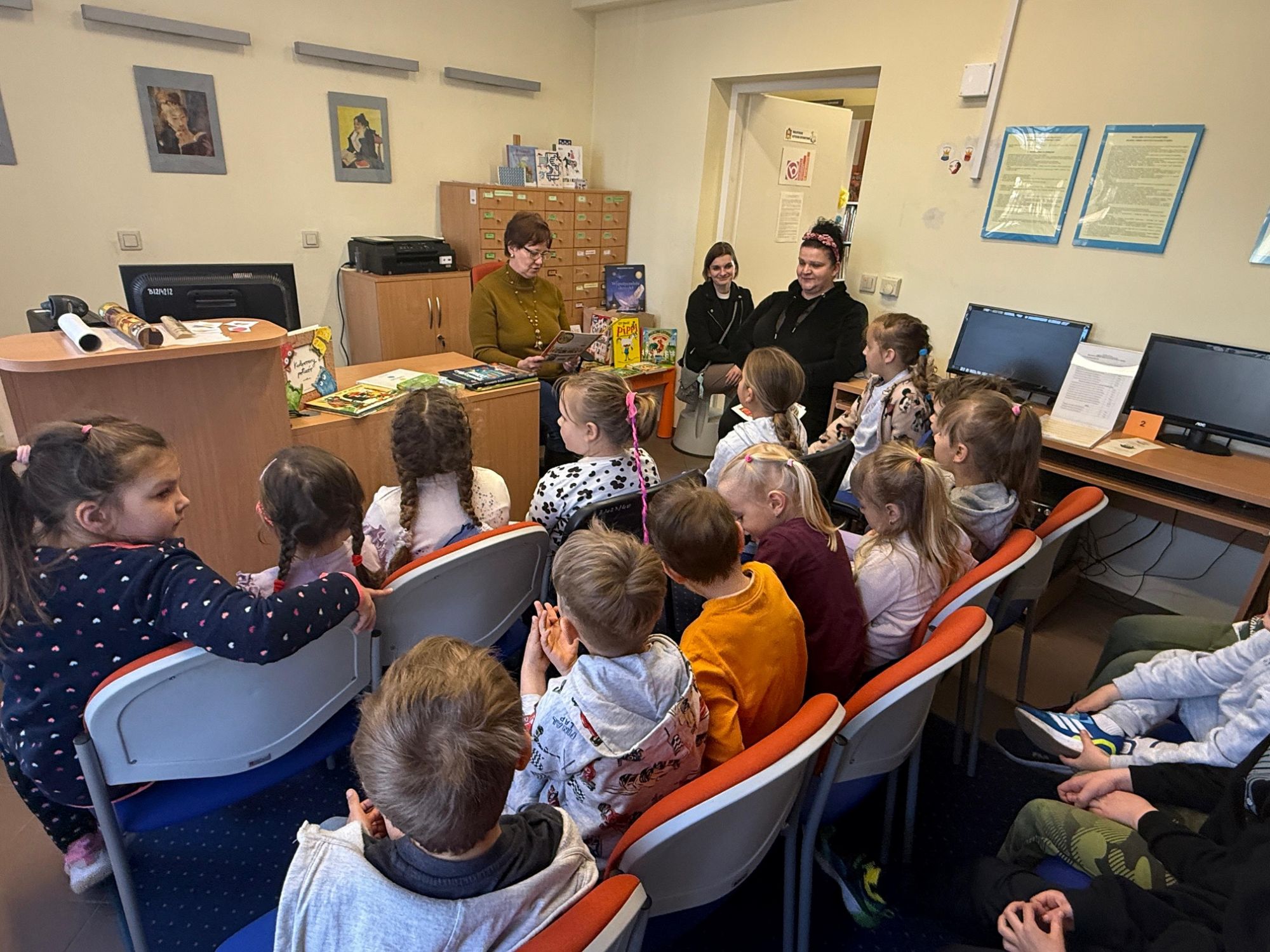 Czytanie przez bibliotekarkę bajki przed grupą dzieci.