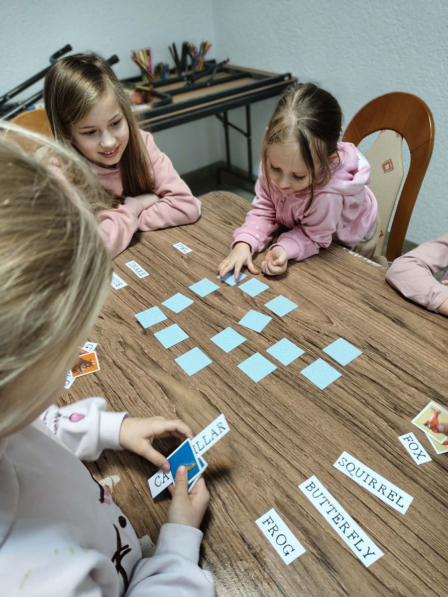 Dziewczynki siedzące przy stole grają w grę memory.