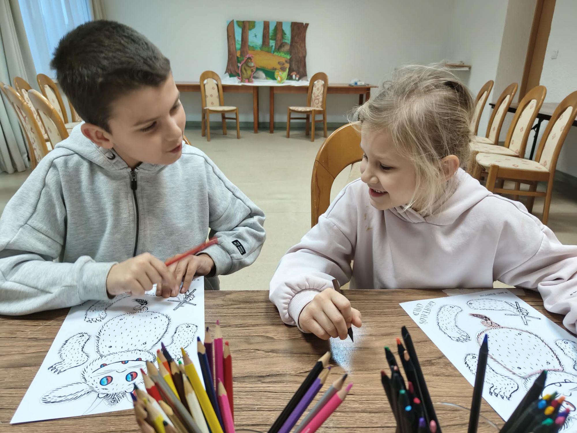  Chłopiec i dziewczynka rozmawiają kolorując kolorowankę