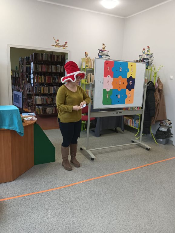 Bibliotekarka w mikołajkowym kapeluszu przemawia do dzieci