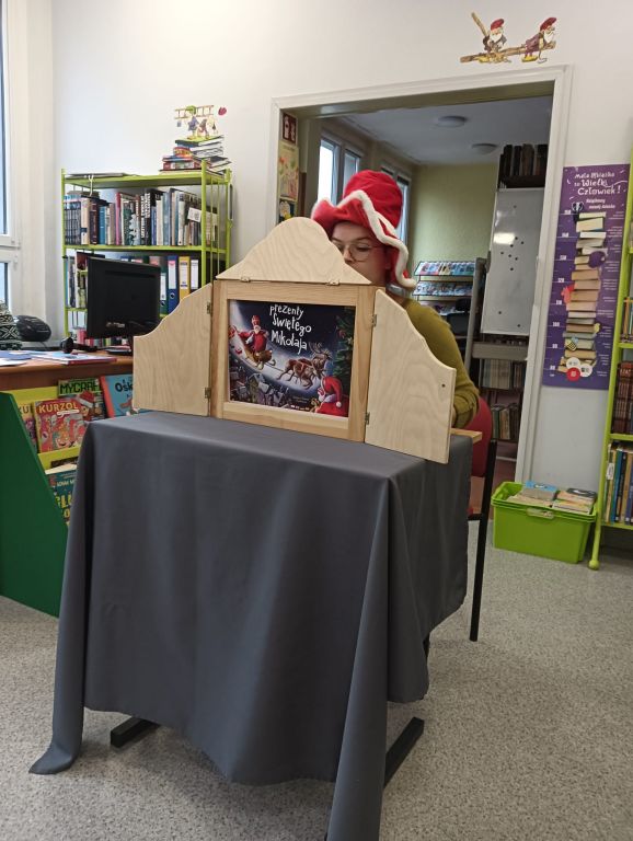 Bibliotekarka czyta bajkę w formie teatrzyku kamishibai