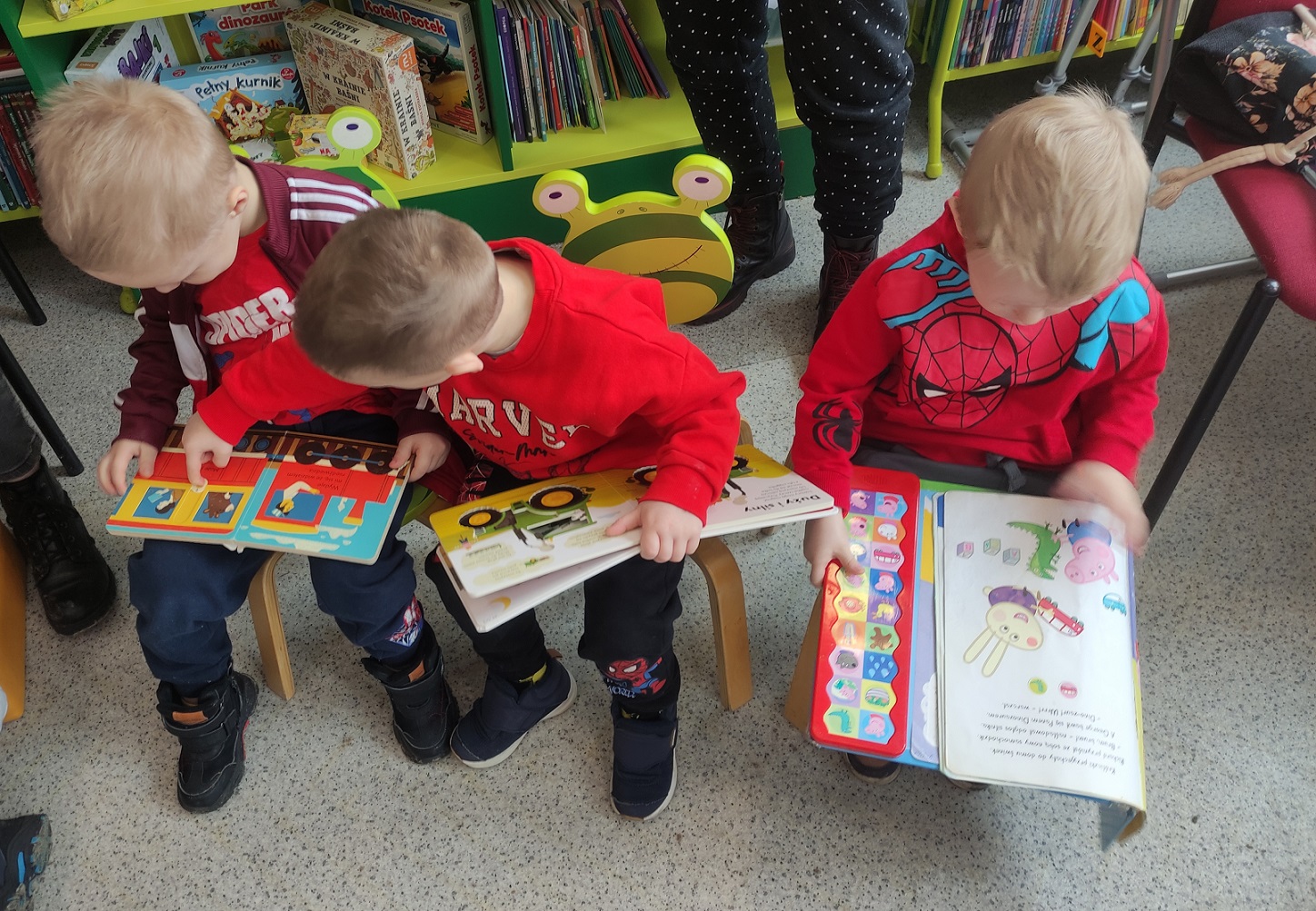 Trzech chłopc&oacute;w ogląda książki.