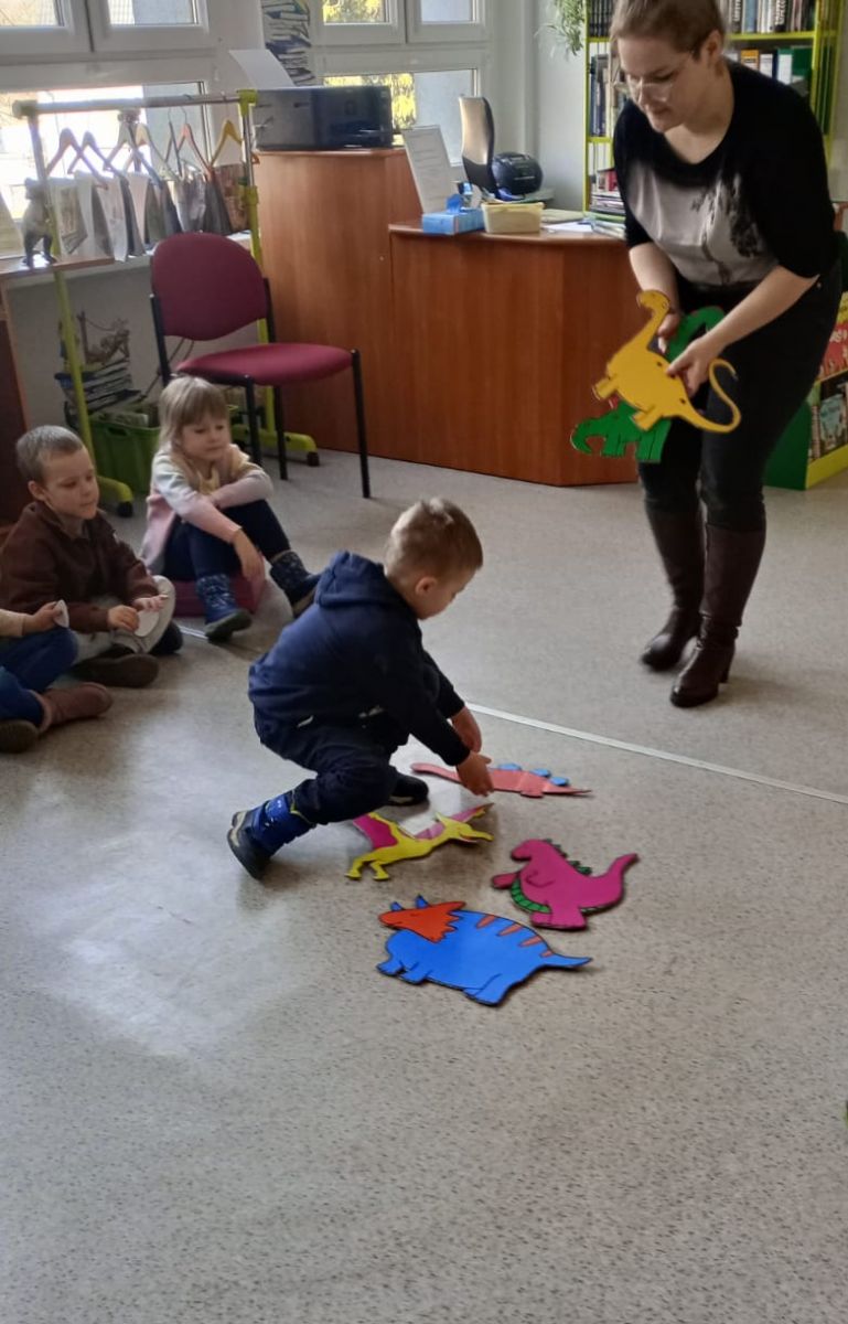 Dziecko wybiera z grupy dinozar&oacute;w tego, kt&oacute;ry spełnia warunki postawione w czasie zabawy pytania o ilość płytek na grzbiecie.