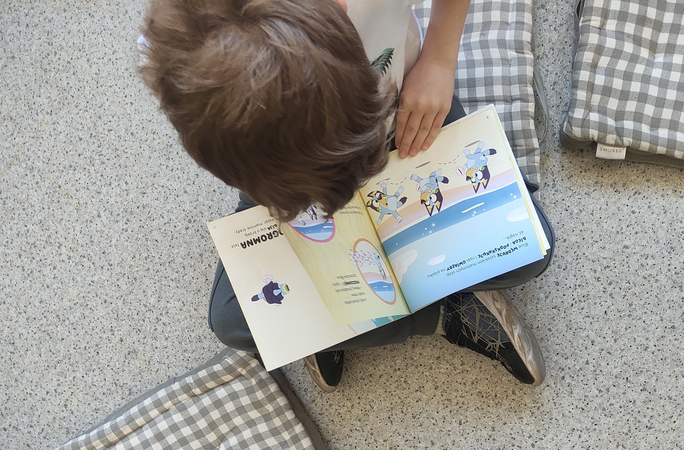 Chłopczyk przegląda książeczkę "Bluey", dostępną w bibliotece.