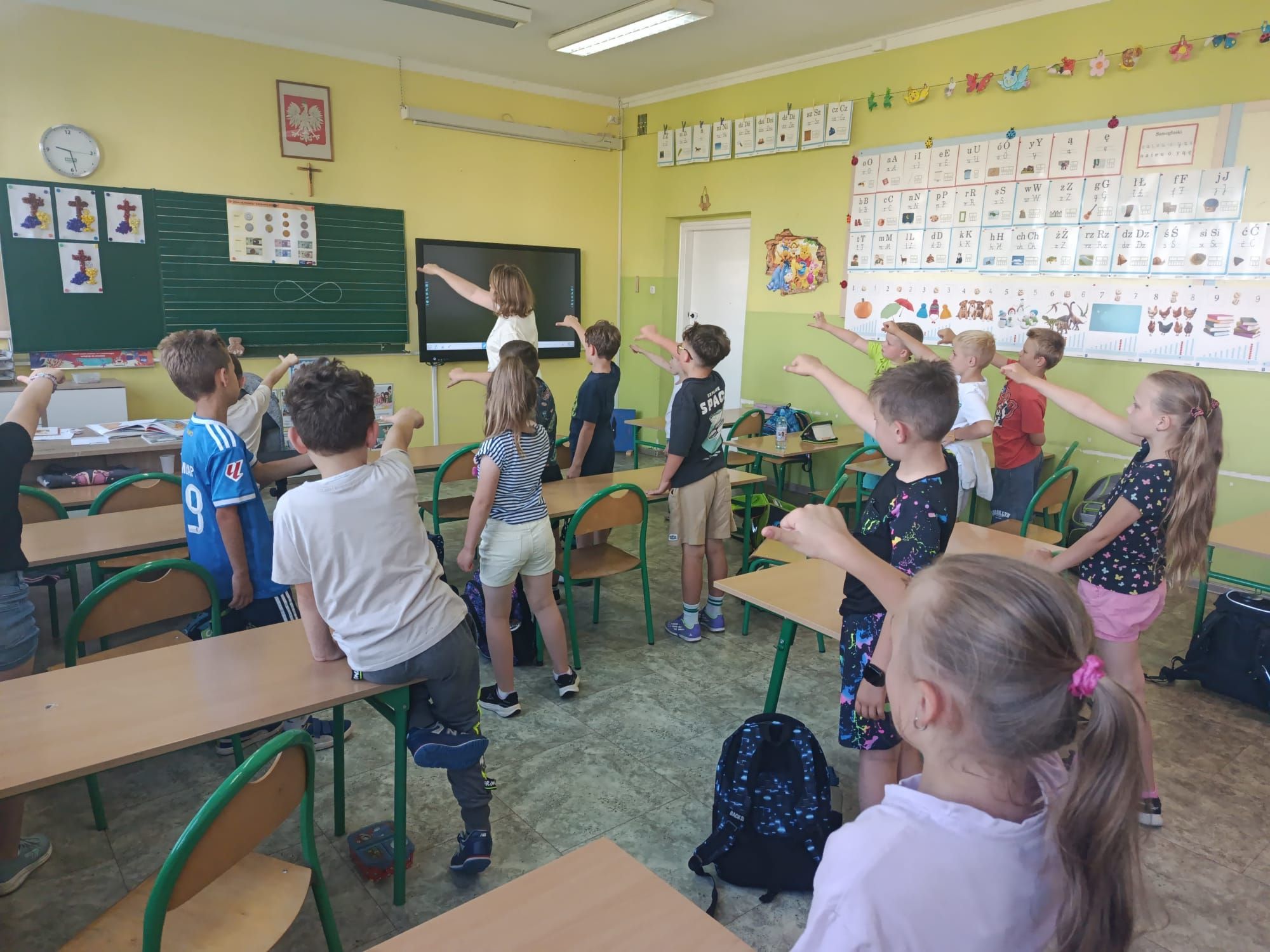 Dzieci stoją i wykonują w powietrzu leniwe &oacute;semki