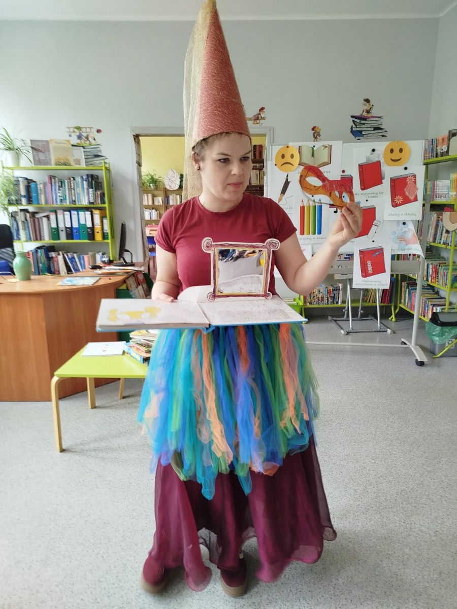 Wr&oacute;zka pokauzje dzieciom  książkę z lustrem i maską superbohatera.