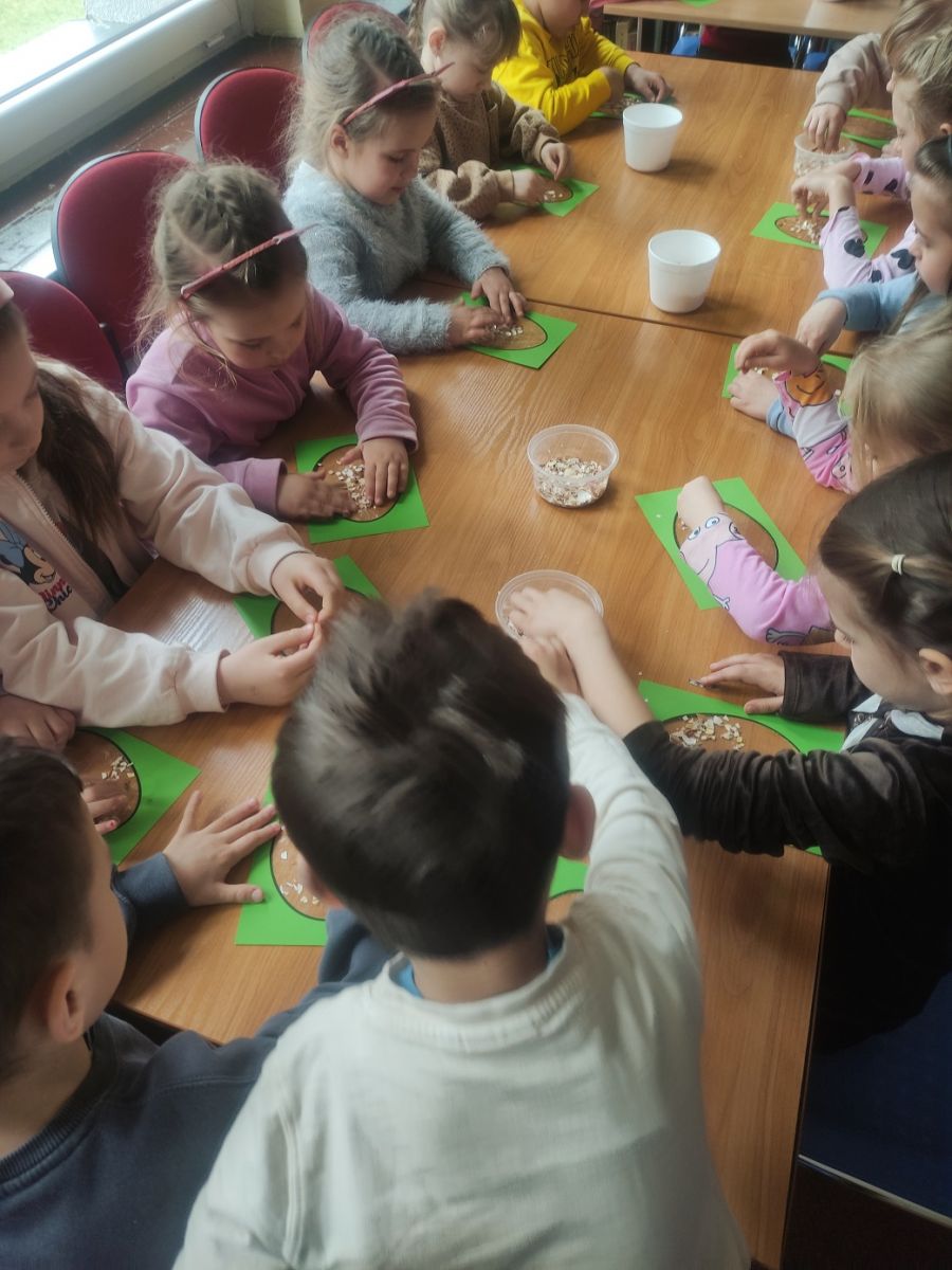 Dzieci wykonują prace plastyczne wyklejając obrazek skorupkami jaj.