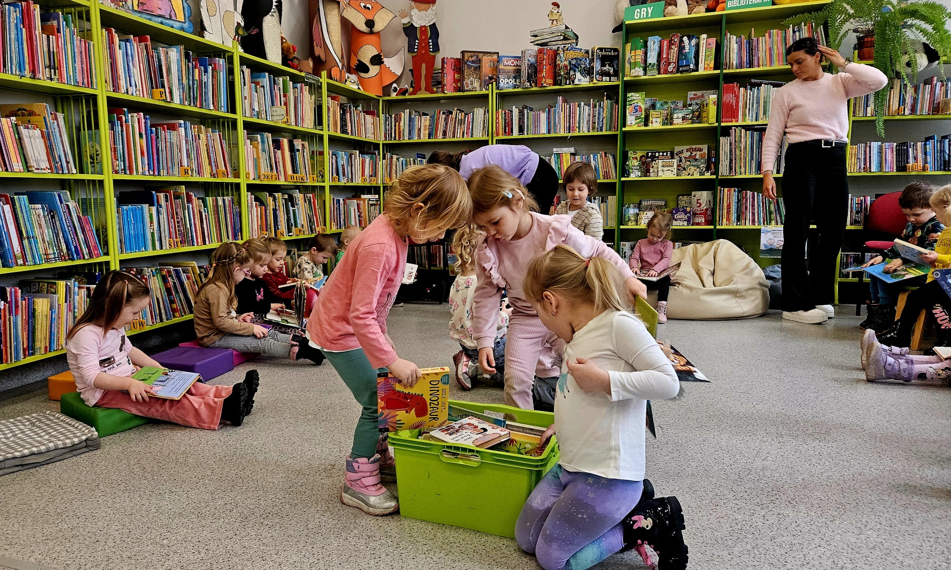 Dzieci oglądają książki w bibliotece.