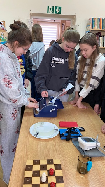 Dziewczyny pr&oacute;bują pisać na maszynie  z alfabetem Braille'a