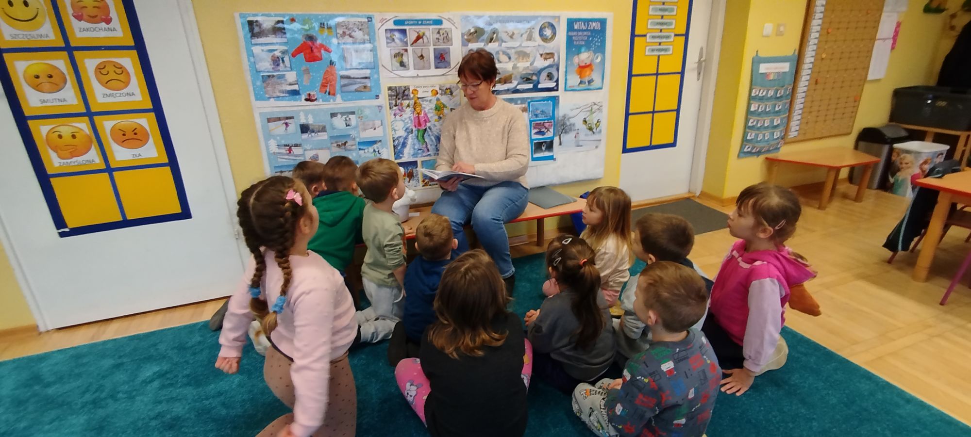 Pani czyta dzieciom fragmenty książki "Kraina Lodu"
